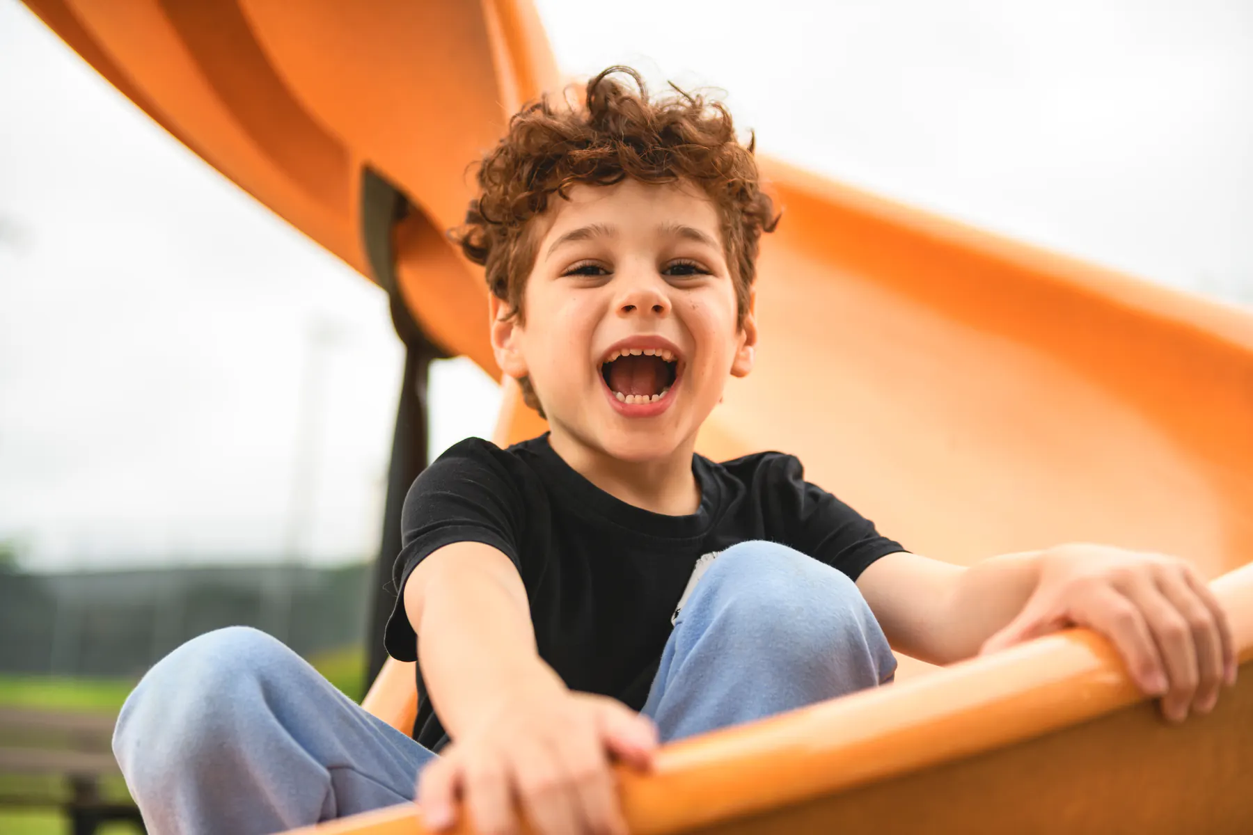 Child laughing while riding down a playground slide