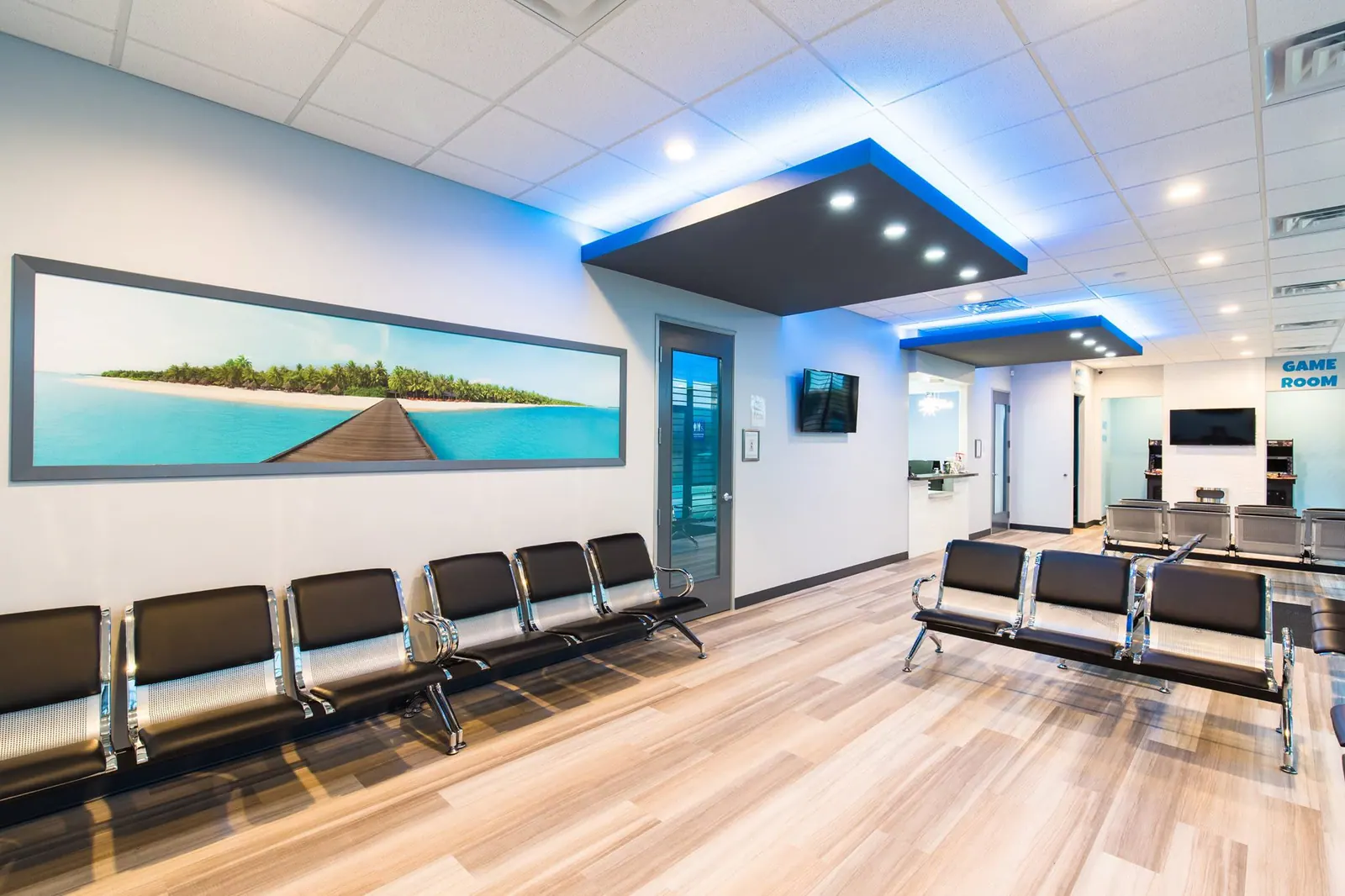 Main Fresca Dental waiting room with black seating and a large coastal wall photograph