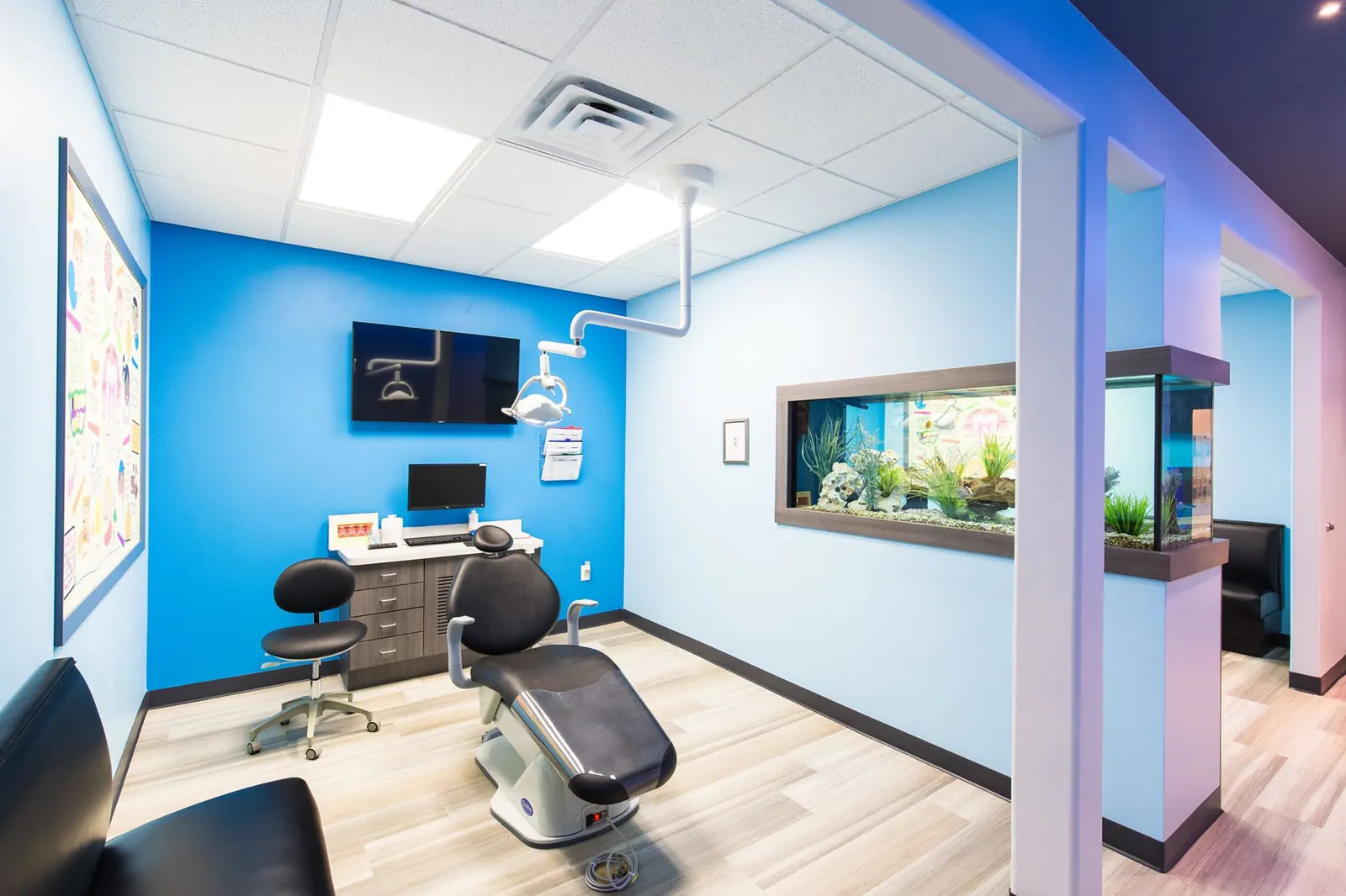 Wide view of a treatment room with a dental chair and aquarium